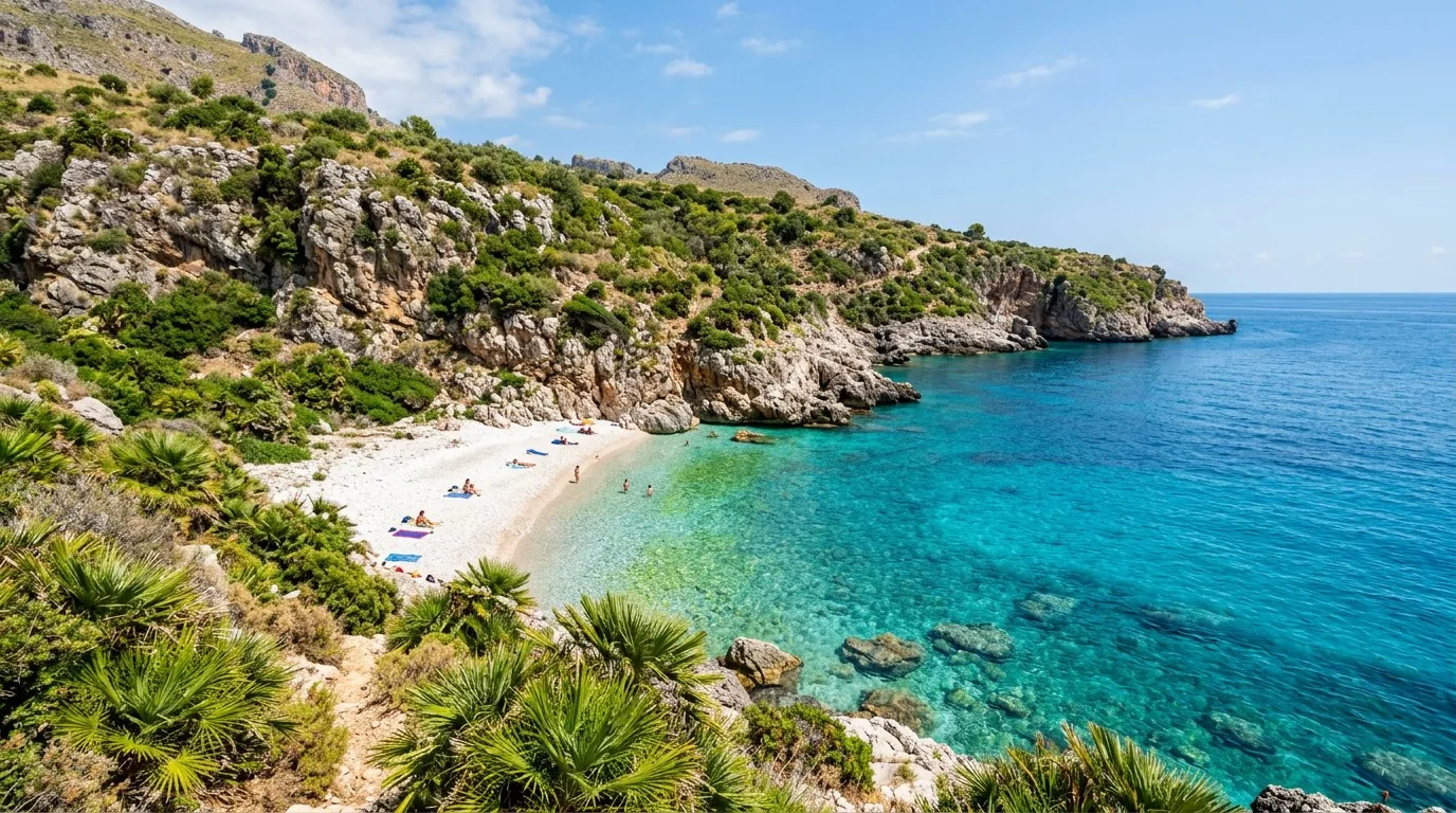 Cala Capreria near the reserve's southern gate — pebbles, dwarf palms and water that shades from green to blue.